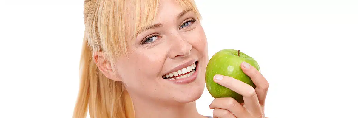 Mentadent. Una ragazza morde una mela verde grazie a denti e gengive sane