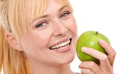 Mentadent. Una ragazza morde una mela verde grazie a denti e gengive sane