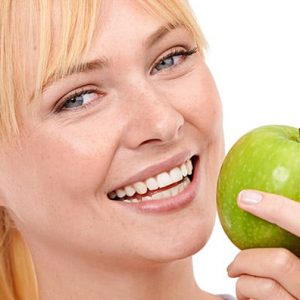 Mentadent. Una ragazza morde una mela verde grazie a denti e gengive sane